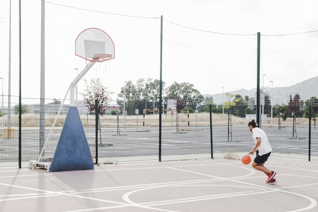 Man practicing basketball near hoop in outdoors court Free Photo