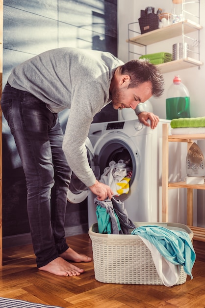 Premium Photo | Man putting clothes into washing machine