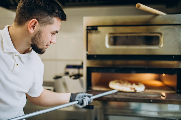 Free Photo Man Putting Pizza In Oven At Pizzeria