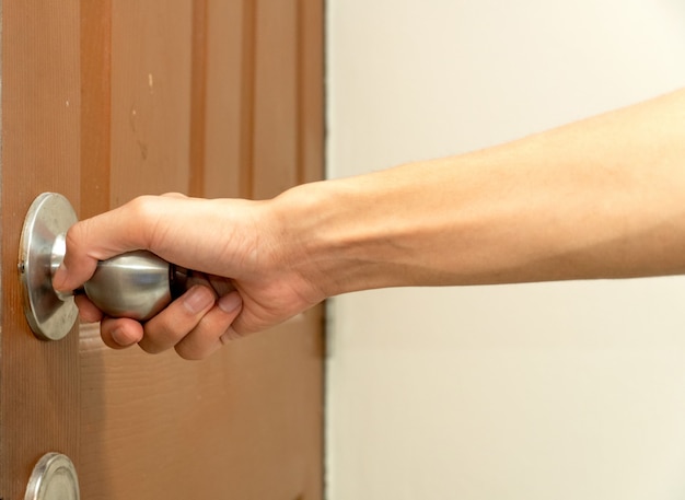 Man S Hand Reaching To Door Knob Opening The Door Brown