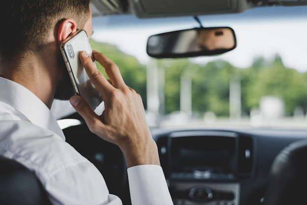 Man's talking on smartphone while driving car Free Photo