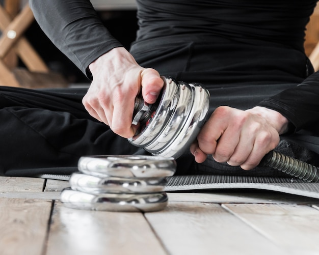 Man setting up discs for dumbbell Free Photo