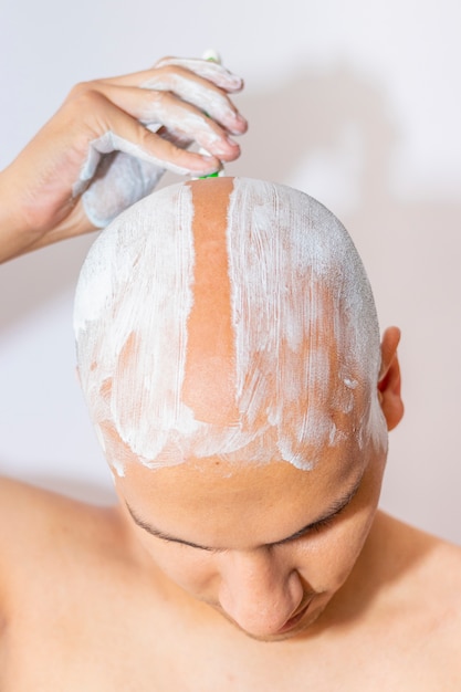白い泡を使用して頭を剃る男 プレミアム写真