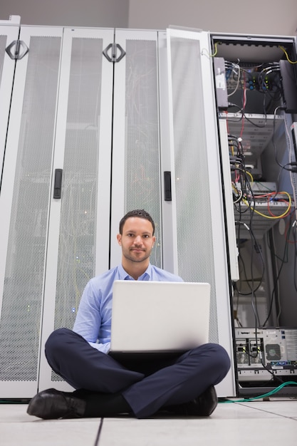 Man sitting in front of servers with his laptop Premium Photo Man sitting in front of servers with his laptop Premium Photo