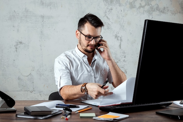 Man sitting at a table in the office, talking on the phone, decides an important question. the concept of office work, a startup. copy space. Premium Photo