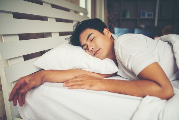 朝のベッドで寝る男 無料写真