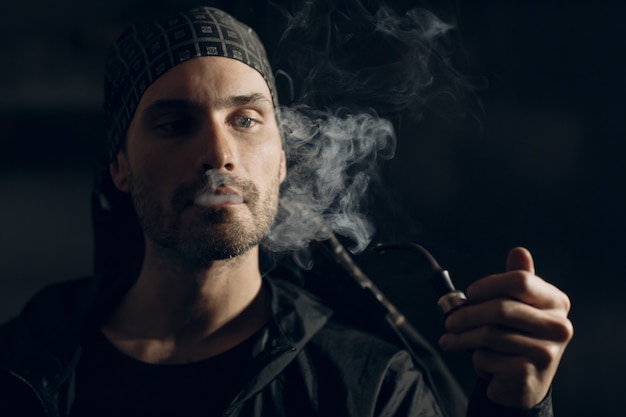 Premium Photo | Man smoking a pipe on dark background. back lit profile ...