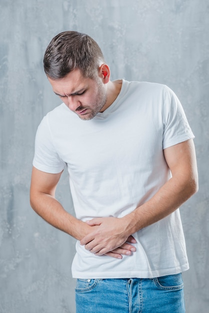 Man standing against gray background suffering from abdominal pain Free Photo