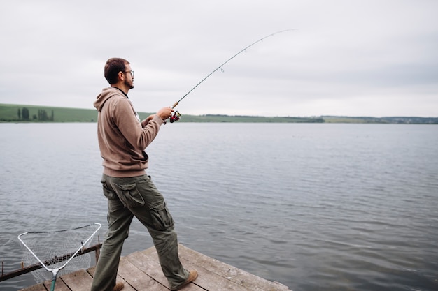 Free Photo | Man standing on pier fishing in lake