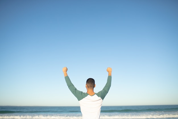 Free Photo | Man standing with arms up on the beach