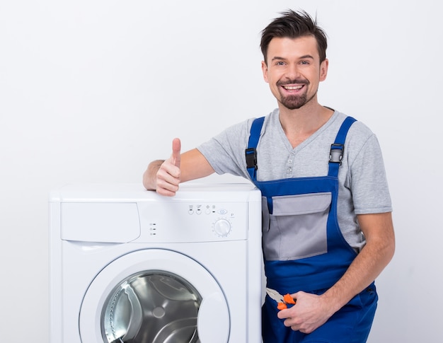 Man stands near a washing machine showing a thumbs up. Premium Photo