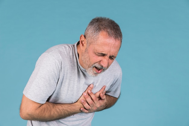 Man suffering from chest pain on blue backdrop | Free Photo