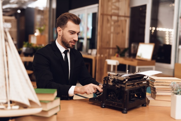 Premium Photo | Man in suit is sitting at table with an old typewriter.