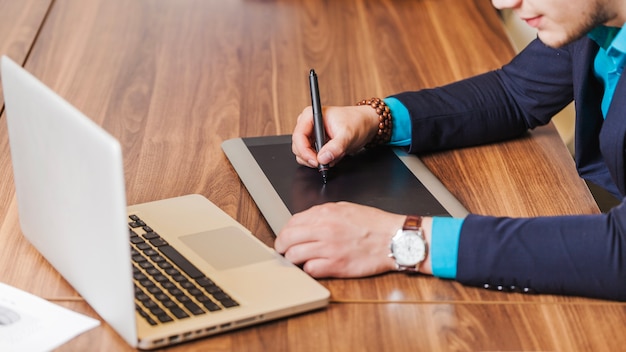 Man in suit sitting at desk drawing | Free Photo