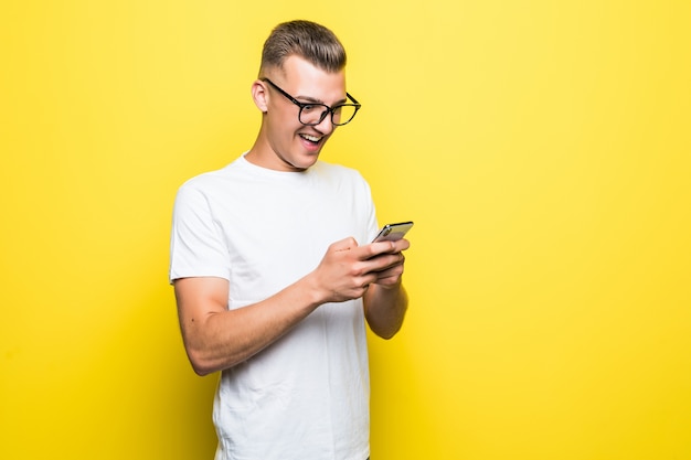 Man in t-shirt and glasses makes something on his phone and takes selfie pictures isolated on yellow background Free Photo
