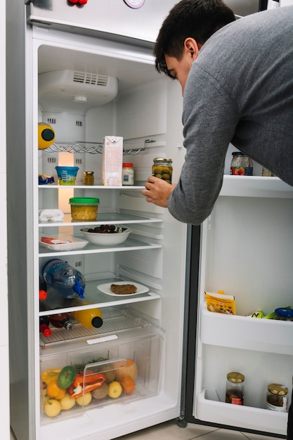 Man taking olive pickle from refrigerator Free Photo