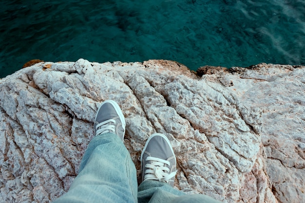 Man in trekking shoes stands on the edge of a cliff. concept-travel, walks by the sea, suicidal thoughts, depression. Premium Photo