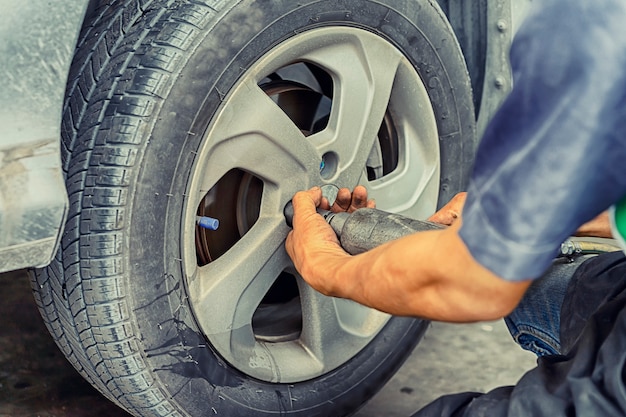 Man using car mechanic block the wind wheel. to check your tires and brake for car.auto mechanic preparing for the work. Premium Photo