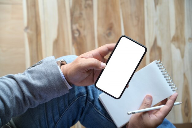 Man using mobile smartphone while writing note Premium Photo