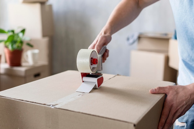 Man using scotch tape on box ready for moving out Free Photo