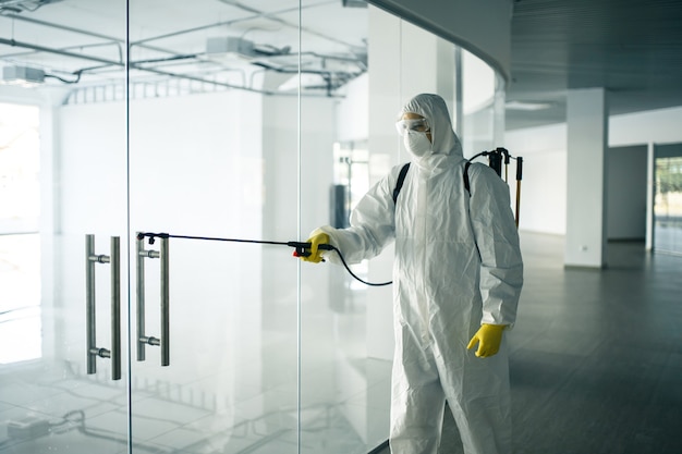 Premium Photo | A man wearing disinfection suit spraying with sanitizer ...