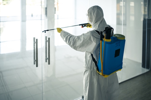 Premium Photo | A man wearing disinfection suit spraying with sanitizer ...