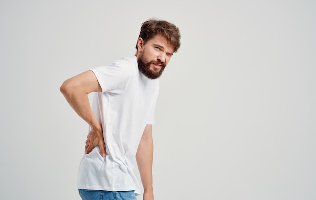 Premium Photo | A man in a white t-shirt touches his back with his hand ...