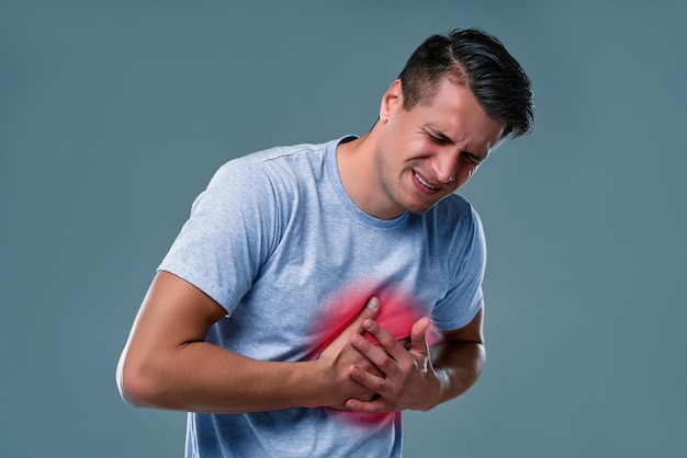 Man in white t-shirt with heart pain on gray room Premium Photo