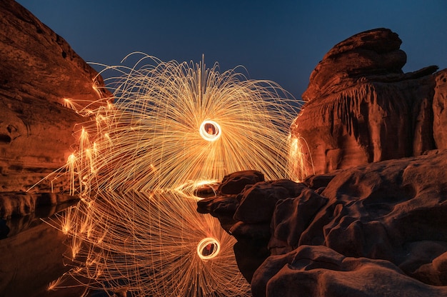 Premium Photo Man Wielding Rounded Burning Fire Spark From Steel Wool In Rock Rapids Of Grand Canyon Reflection On River At Hat Chom Dao