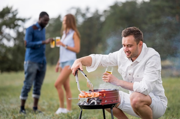 友達のためにバーベキューに参加するビールを持つ男 無料の写真