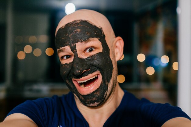 Premium Photo Man With Charcoal Mask On His Face Taking Selfie