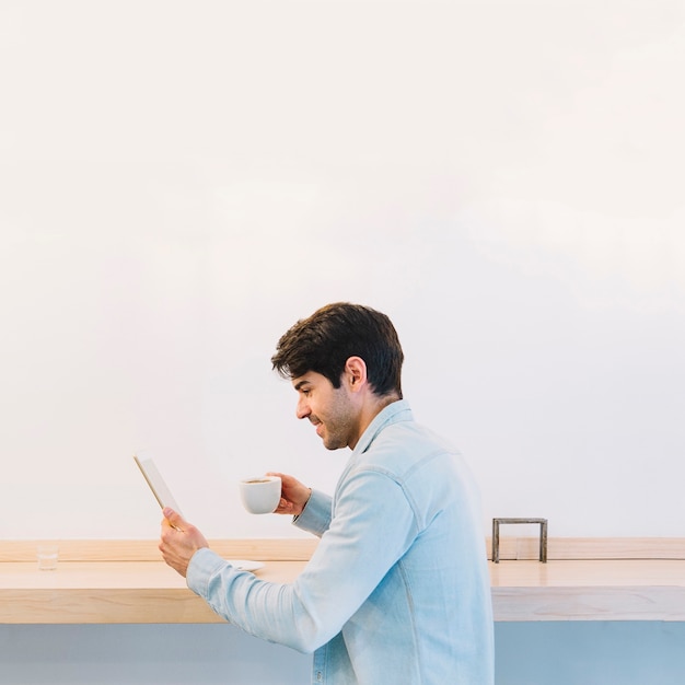 Man with coffee using tablet Free Photo
