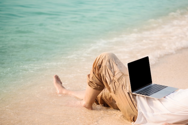 Man with computer on the beach. working on computer at outdoors while