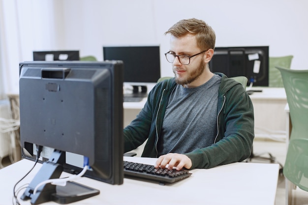 Man with the glasses. student in computer science class. person uses a computer. Free Photo