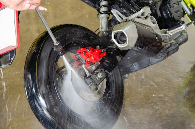 Premium Photo | A man with a high pressure water gun washing a motorcycle