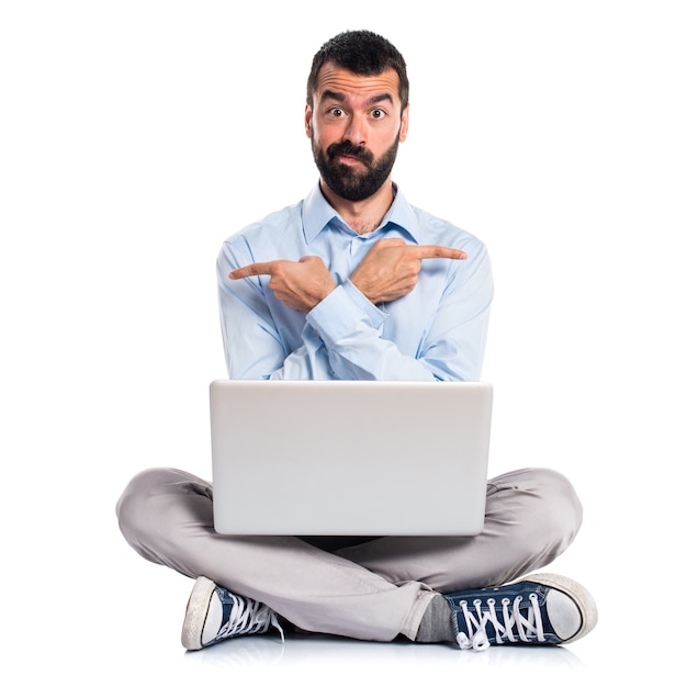 Man with laptop pointing to the laterals having doubts Free Photo
