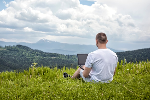  Man with laptop sitting on green grass