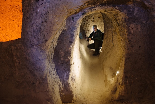 Premium Photo | Man with lights exploring caves in derinkuyu ancient ...