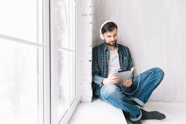 Man with tablet relaxing near window Free Photo Man with tablet relaxing near window Free Photo