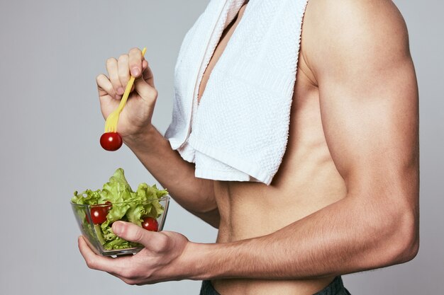 A man with a towel on his shoulders a plate of salad healthy food diet. Premium Photo