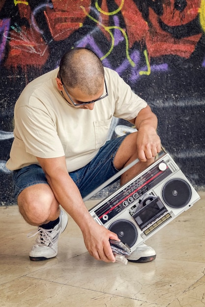 Premium Photo Man With A Vintage Boombox Sitting On Street Next To A Wall With Graffiti