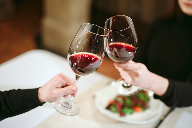 Man and woman drinking red wine. in the picture, close-up hands with glasses. Premium Photo