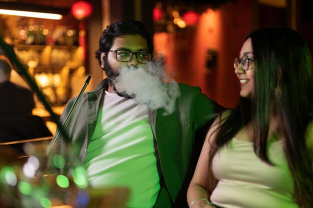 Premium Photo Man And Woman Relaxing By Vaping From A Hookah In A Bar