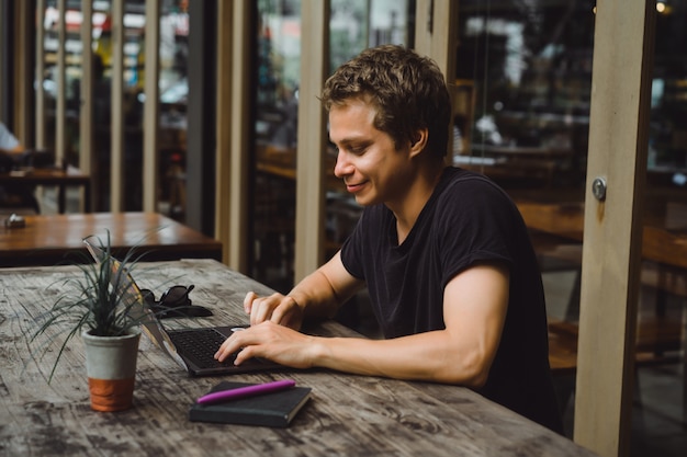 Free Photo | Man working with a laptop in a cafe on a wooden table