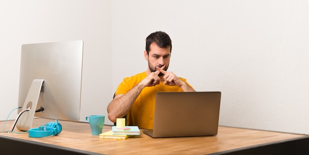 Man working with laptot in a office showing a sign of silence gesture Premium Photo