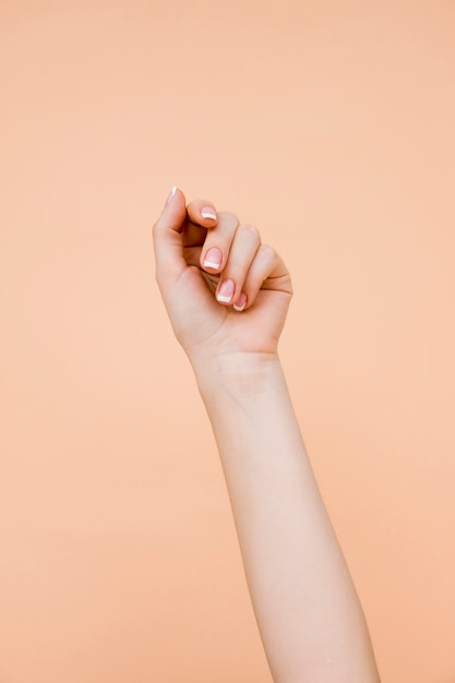 淡いオレンジ色の背景に手入れの行き届いた女性の腕 プレミアム写真