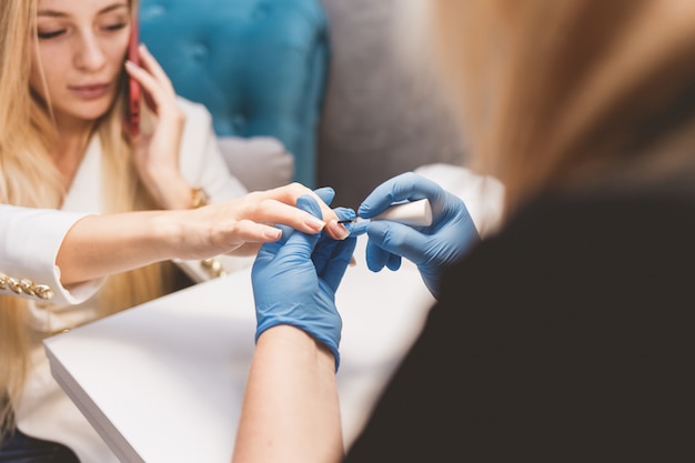 Premium Photo | Manicurist makes gel polish for her client