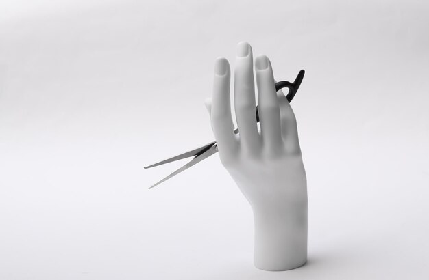 Premium Photo | Mannequin hand holding hair scissors on white ...