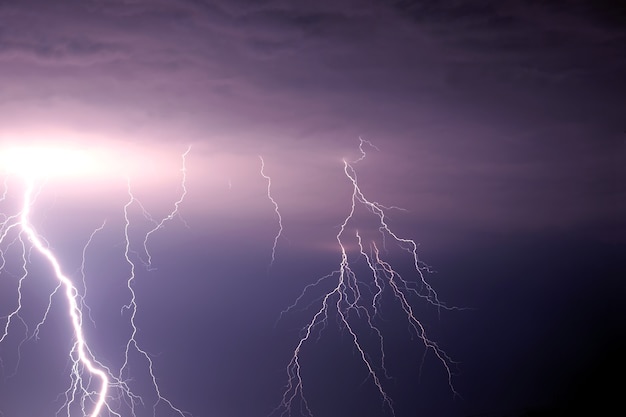 激しい紫雨の雲の下の荒れ模様の空に多くの明るい稲妻放電 プレミアム写真