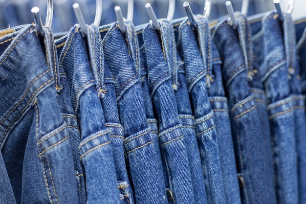 Premium Photo | Many denim jeans hanging on a rack